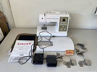 Overall lot with Singer Confidence Quilter sewing machine, extension table, manual, cords, foot pedal, attachments