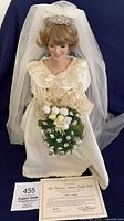 Full doll seated, showing gown, bouquet, veil, certificate
