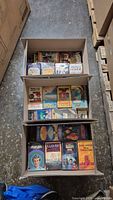 Three cardboard boxes showing spines and covers of assorted paperback sci-fi/fantasy books