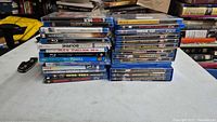 Two stacks of assorted Blu-ray cases on a table