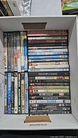 Box containing full lot of DVDs, showing vertical and horizontal stacks