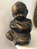 Front view of seated bronze boy Buddha with crossed arms