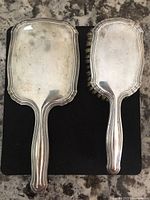 Front of mirror and back of brush showing silver backs and handles