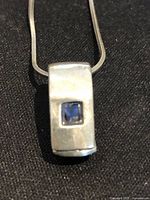 Close-up of pendant showing sapphire and silver surface