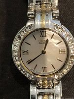 Close-up of watch face showing mother-of-pearl dial, Roman numerals, crystal bezel and two-tone bracelet links