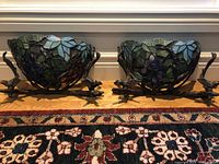 Both stained glass bowls on bronze stands side by side