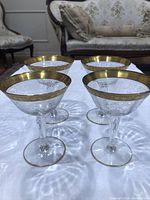 Four Tiffin Rambler Rose crystal glasses showing gold rims and stems