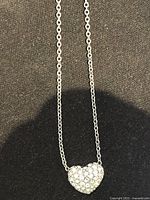 Necklace close-up showing heart pavé pendant and chain texture