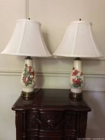 Pair of matching floral ceramic table lamps on wooden table