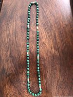Full view of the malachite bead necklace laid flat to show length and bead arrangement