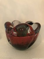 Front view of red and green sommerso glass candle holder showing scalloped clear rim