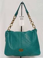 Front view of turquoise leather Fossil Quinn handbag displaying turn-lock clasp and chain/leather strap