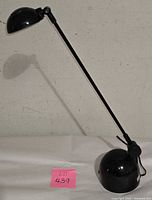 Full view of black adjustable table lamp showing spherical base, long arm, dome shade