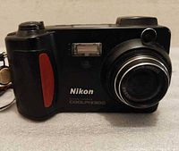 Front view of Nikon COOLPIX 800 camera showing lens, flash, red grip