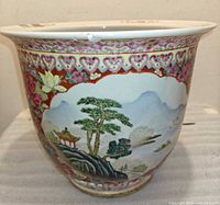 Front view of porcelain jardinière showing landscape panel and floral border