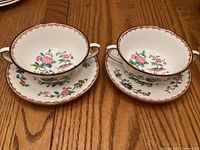 Two Coalport Pembroke cream soup bowls with saucers displayed