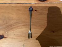 Front view of fork showing enamel coronation emblem and three tines