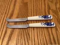 Pair of cheese knives showing serrated blades and decorated handles