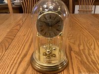 Front view showing full clock with glass dome and brass base