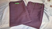 Both folded purple curtain panels showing texture and grommet tops