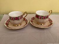 Two matching Royal Albert teacups on saucers showing rose pattern and gold trim