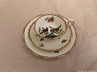 Front view of stacked tea cup, saucer and plate showing bird and floral design