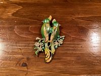 Front view of brooch showing enamelled cockatiels, branch and rhinestones