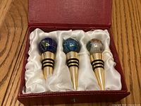 Three gemstone globe wine stoppers in satin-lined box