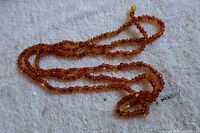 Full view of amber-tone bead necklace coiled on cloth