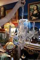 Full view of chandelier held by chain showing four arms, glass drops, chrome canopy