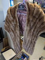Full view of fur shawl hanging, showing exterior texture and shoulder shape