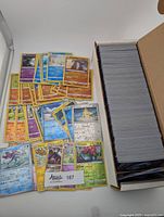 Stack of cards in storage box with spread showing assorted reverse-holo Pokémon cards