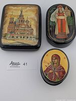 Front view of all three boxes closed showing painted scenes