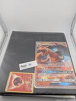 Front of black binder with Charizard GX jumbo card and one regular energy card for scale