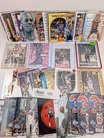 Front view of assorted sleeved and unsleeved NBA cards laid out, showing variety of players and sets