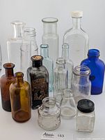 Group shot of all 14 glass bottles and jars showing colors, sizes and shapes