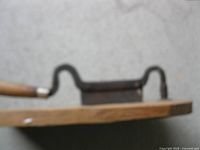 blurry top view of tobacco cutter showing handle, iron arm and blade