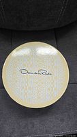 Round beige patterned box lid with Oscar de la Renta logo