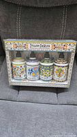 Front view of boxed set showing four decorated ceramic soap dispensers