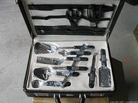 Open briefcase showing first layer with cooking utensils, handheld grater and one missing scissor slot