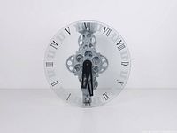 Front view of glass wall clock showing Roman numerals and central gears