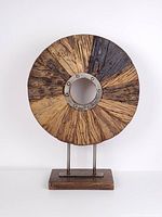 Front view of round wood sculpture showing metal ring and grain pattern
