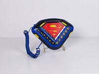 Front view of Superman shield telephone with handset on cradle