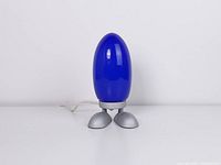 Front view of blue glass egg lamp on silver feet base, cord visible