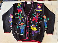 Front view of cardigan laid flat showing appliqué design and buttons