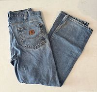 Full view of folded Carhartt jeans showing logo patch