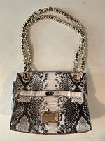 Front view showing faux snakeskin pattern, flap, logo plaque, double chain straps