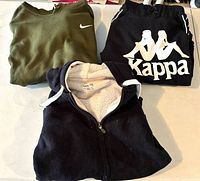 Three folded hoodies: olive Nike, black Kappa, black Roots zip