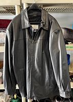 Front view of black leather coat on hanger