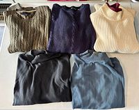 Five sweaters laid out flat